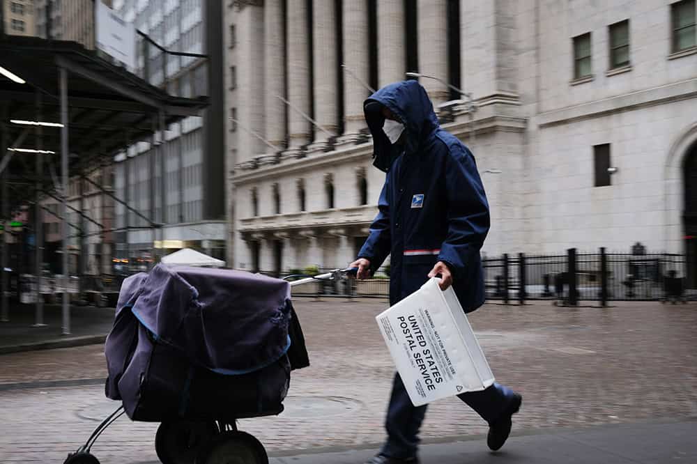 A mail carrier walks along Wall Street