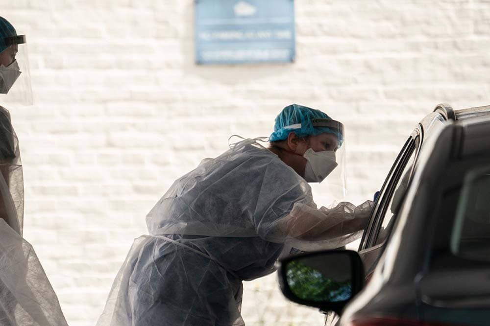 Image of a physician giving a covid test through a car window.