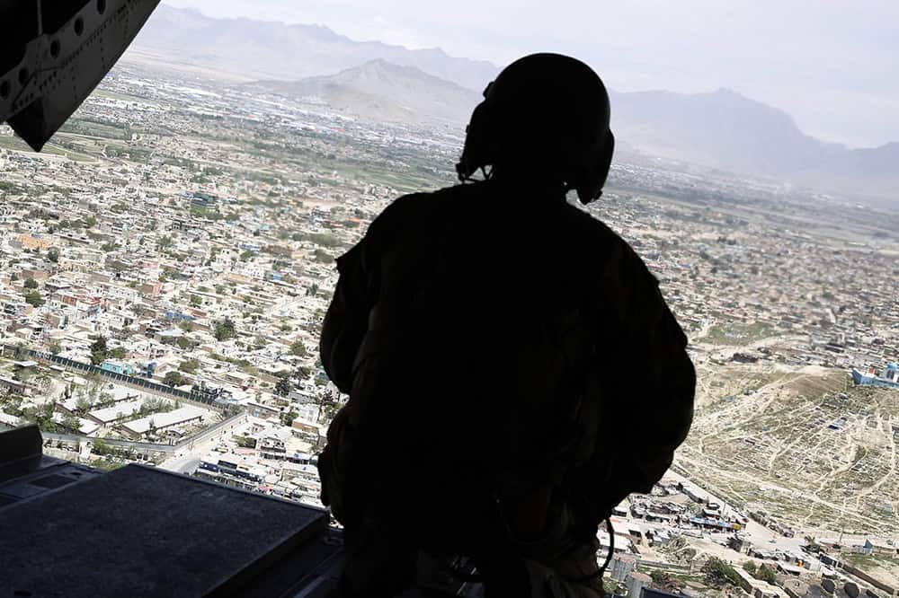 A U.S. soldier mans a gun at the back gate aboard a helicopter