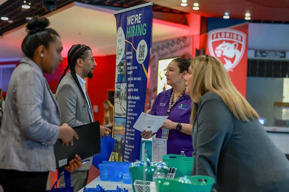 Image of people speaking with recruiters at a job fair.