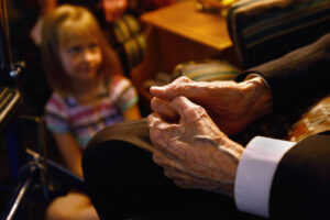 Small child listening to an elderly person.