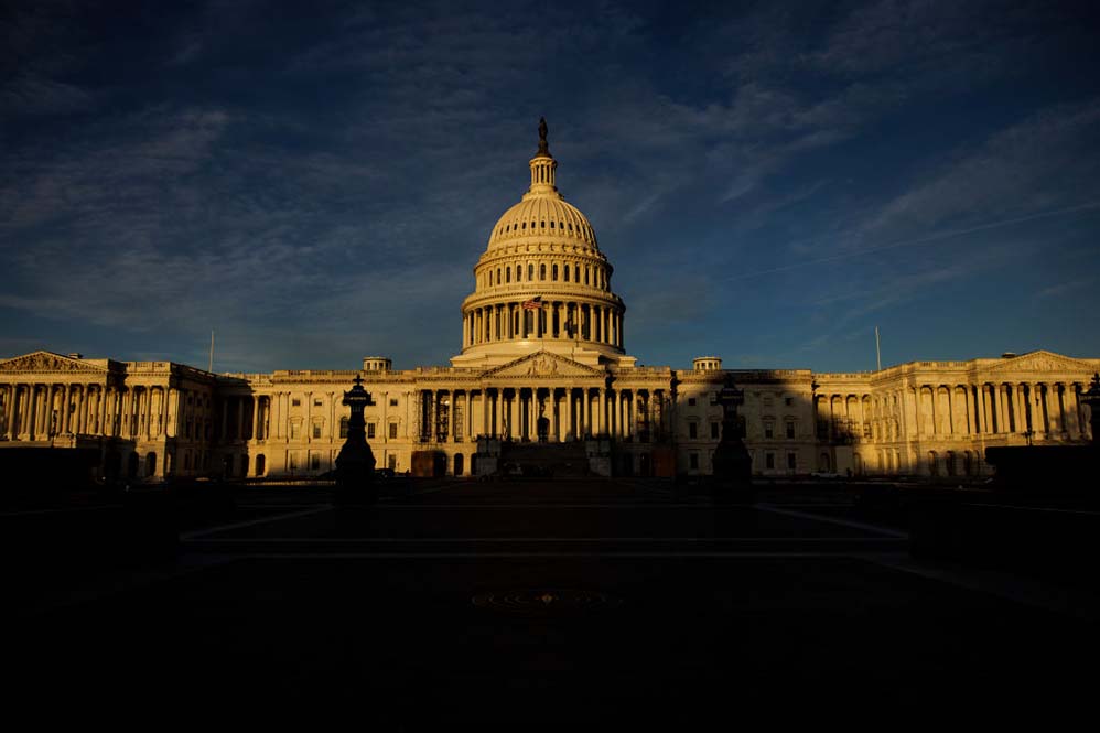 Image of the U.S. Capitol half in shadow during sunset.