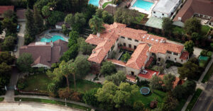 Image is an aerial view of a mansion in a wealthy neighborhood.