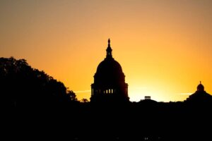 Image of the U.S. Capitol back lit in shadow from a sunset.