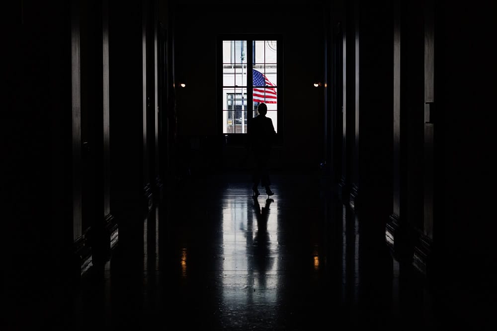 Image of a dark hallway with a U.S. flag at the end